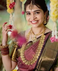 a woman in a sari is smiling and holding a flower garland on her head