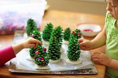 small pine cones are being made to look like christmas trees