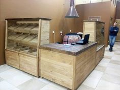 a woman standing in front of a wooden counter with drawers and laptop computer on it