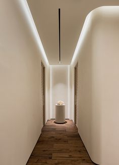 a long hallway with a clock on the wall and wooden flooring in front of it