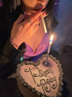 a woman blowing out the candles on her heart shaped cake