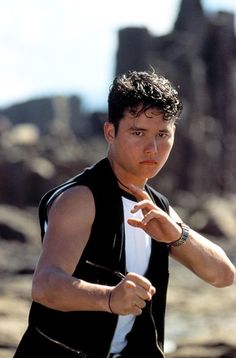 a man pointing at something while wearing a black vest