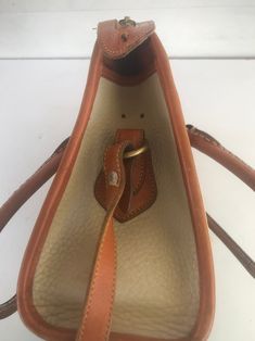 "Dooney & Bourke Beige Camel Handbag Top Handle Convertible Crossbody Bag Removable brown crossbody strap with drop of 20\" made of brown leather and marked bfrass rolled leather top handles with slight wear top zip closure two internal pockets one on back wall and front wall with snap closure one internal zipper pocket internal Dooney Bourke tag 4 brass feet on bottom with some wear Dimensions: 12 1/2\" L x 8 1/4\" H x approx. 4 1/2\" D on exterior beige pebbled leather, I see one small str Convertible Crossbody Bag, Front Wall, Brown Crossbody, Top Handle Bags, Crossbody Strap, Leather Top, Dooney Bourke, Pebbled Leather, Snap Closure