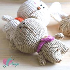 two crocheted stuffed animals sitting on top of a wooden table next to yarn