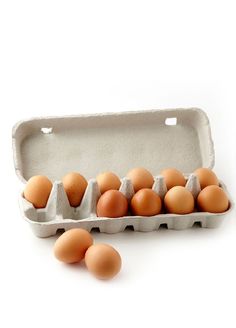 an egg carton filled with brown eggs on a white surface, next to two dozen eggs