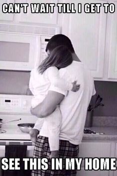 a man holding a baby in his arms while standing next to a stove top oven