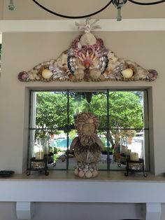 a decorative window frame with seashells and candles on it in front of a large window