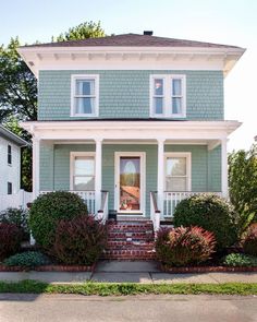 a green house with white trim and two story