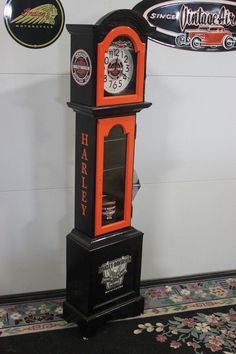 an orange and black grandfather clock with harley logos on the front is standing upright against a wall