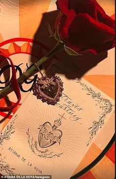 a red rose sitting on top of a piece of paper next to a heart shaped brooch