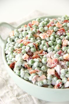 a bowl filled with peas and bacon on top of a table