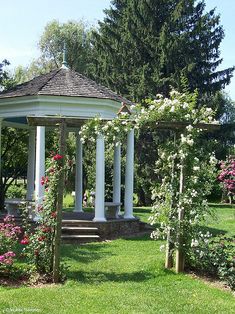 a white gazebo surrounded by flowers and trees