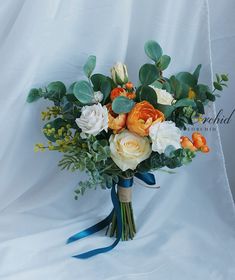 a bridal bouquet with orange and white flowers on a blue ribbon tied around it