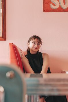 a woman sitting on top of a red couch next to a wall with a sign above it