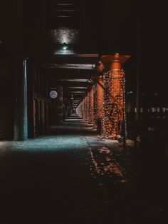 an empty hallway with lights on the sides and dark walls, leading to several stalls