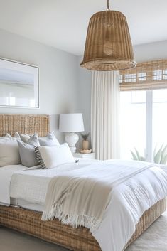 a bed with white linens and pillows in a bedroom next to a large window