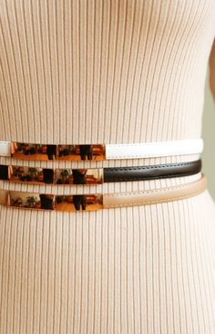 Our CHANEL belt adds a sense of class and sophistication to any outfit! Details include an adjustable waist band, skinny vegan leather material, and slim gold metal front clasp. Available in three colors: Tan, White and Black. Styled with our BENTLEY ribbed sweater dress. Measurements: 39"L x 0.5"W (fits waists between 23"-38") Chic Belts For Fall Parties, Chic Party Belts For Fall, Chic Fall Party Belts, Trendy Gold Belt For Fall, Trendy Gold Belts For Fall, Trendy Belts For Workwear In Fall, Trendy Fall Belts For Workwear, Chic Belts For Spring Night Out, Trendy Fall Workwear Belts