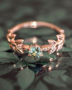 a close up view of a gold ring with leaves on the side and an aqua blue stone in the middle