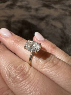 a woman's hand holding an engagement ring with a diamond in the middle, on top of her finger