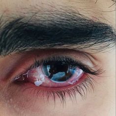 the eye of a man with blue eyes and black hair is seen in this close up photo