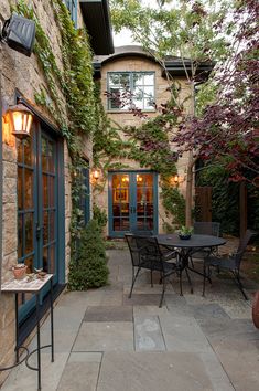 an outdoor patio with tables and chairs next to a brick building that has vines growing up the side of it