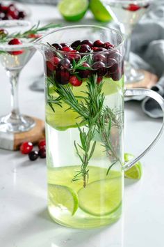 a pitcher filled with liquid and garnished with cranberries