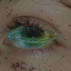 the eye of a child with black spots on it's eyes and an image of a green object in the center