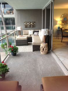 a living room filled with furniture next to a window covered in plants and potted plants