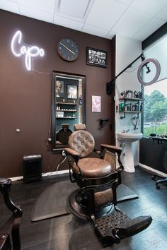 This barber salon studio in Torrance, California has a 30's gangster theme with a television and leather chair to create a throwback feel. Barber Station Setup, Home Barbershop, Barber Setup At Home, Barber Waiting Area, Home Barber Shop Ideas Small Spaces, Small Barber Suite Ideas, Basement Salon, Barber Suite, Barber Setup