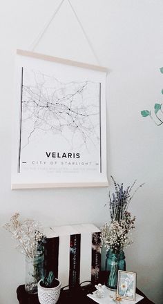 vases with flowers are sitting on a small table in front of a framed poster