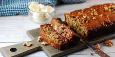 a loaf of banana nut bread sitting on top of a cutting board next to a knife