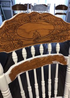 the back of a wooden chair with white paint and wood trimmings on it