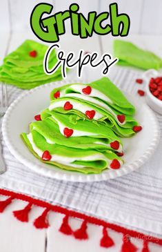 a white plate topped with green crepes covered in white frosting and red hearts