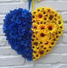 two heart shaped flowers are hanging on a brick wall with blue and yellow daisies