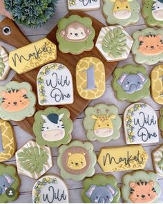 decorated cookies with jungle animals and name tags on wooden board next to potted plant