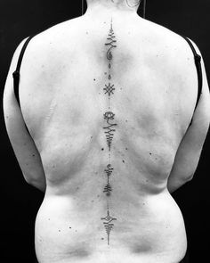 the back of a woman's body with tattoos on it