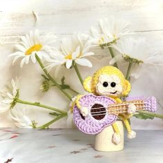 a stuffed monkey holding a purple frisbee next to white flowers and daisies