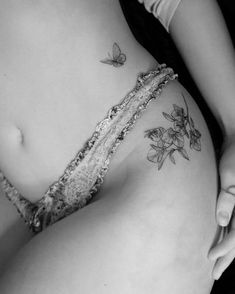 black and white photo of a woman's stomach with flowers on it, butterflies flying around