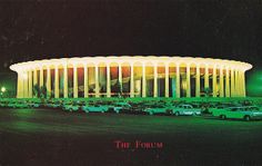 the forum building lit up at night with cars parked in front