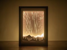 an illuminated box with fireworks coming out of it on a wooden table in front of a wall