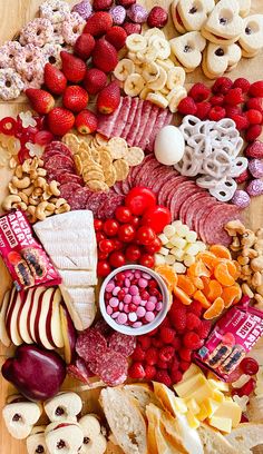 an assortment of food is displayed on a cutting board with fruit, crackers and nuts