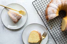 two plates with slices of cake on them next to a cooling rack and a fork