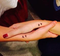 two people holding hands with small tattoos on their fingers and the other hand is crossed