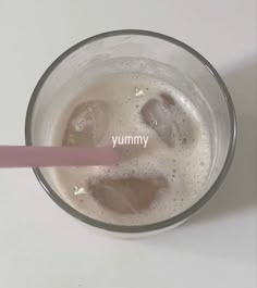 a pink straw sticking out of a glass filled with milk and ice cubes that says yummy