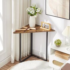 a small table with flowers on it in front of a window and a framed photograph