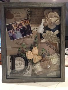 a shadow box filled with wedding items and flowers on top of a white table cloth