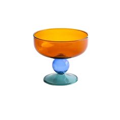 an orange and blue glass bowl sitting on top of a white surface with a circular base