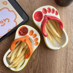 two small plates with french fries and ketchup on them next to a tablet