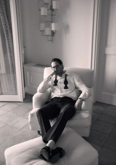 a man sitting in a chair with his feet on the foot rest and wearing a tie