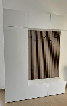 an empty room with white cabinets and wood slats on the wall, along with a radiator